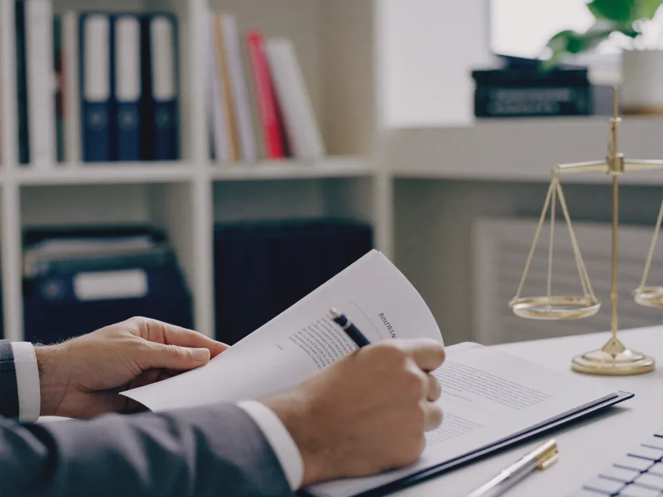 Hands reviewing a printed contract at a tidy law-office desk.